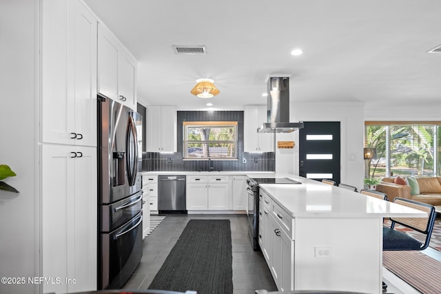 kitchen with stainless steel appliances, island exhaust hood, tasteful backsplash, and white cabinets