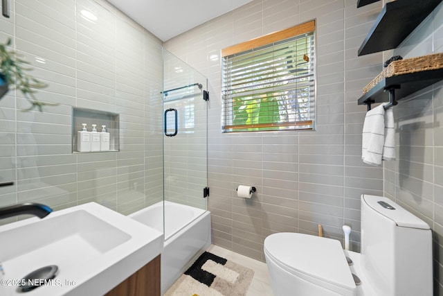 full bathroom featuring sink, tile walls, shower / bath combination with glass door, tile patterned flooring, and toilet