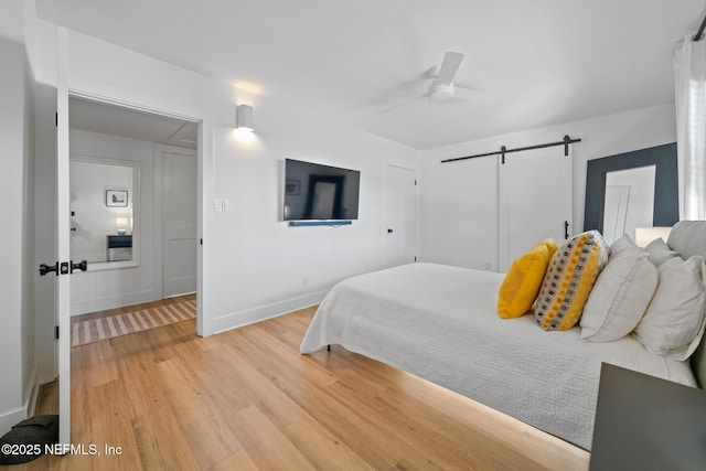 bedroom featuring ceiling fan, a barn door, and hardwood / wood-style floors