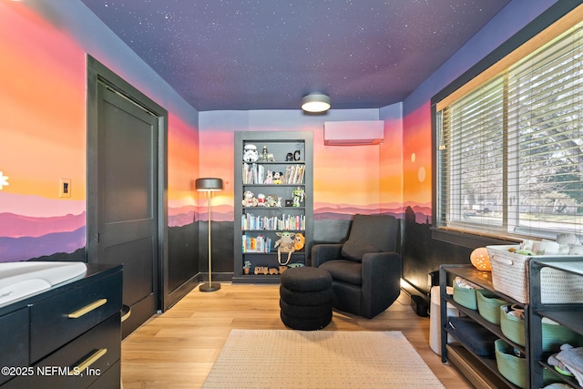 sitting room with light hardwood / wood-style floors and a wall unit AC