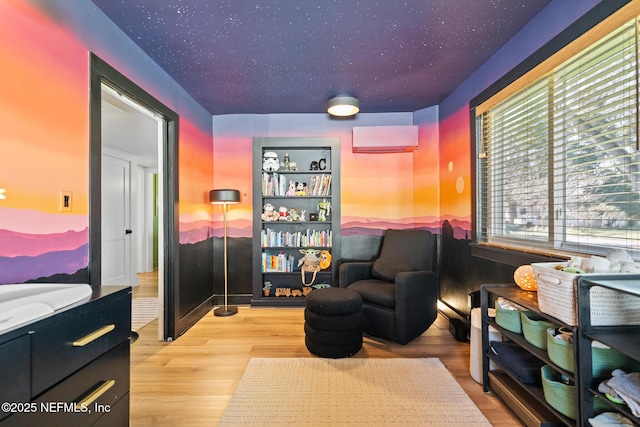 living area featuring a wall mounted air conditioner and light hardwood / wood-style flooring