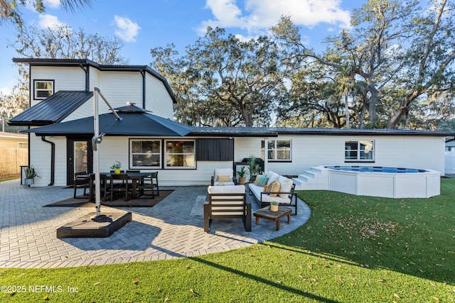 back of house with an outdoor hangout area, a jacuzzi, a patio area, and a lawn