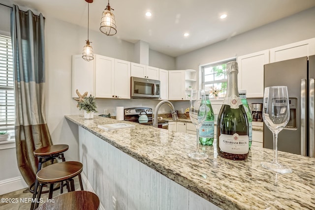 kitchen with light stone countertops, white cabinetry, appliances with stainless steel finishes, and a breakfast bar