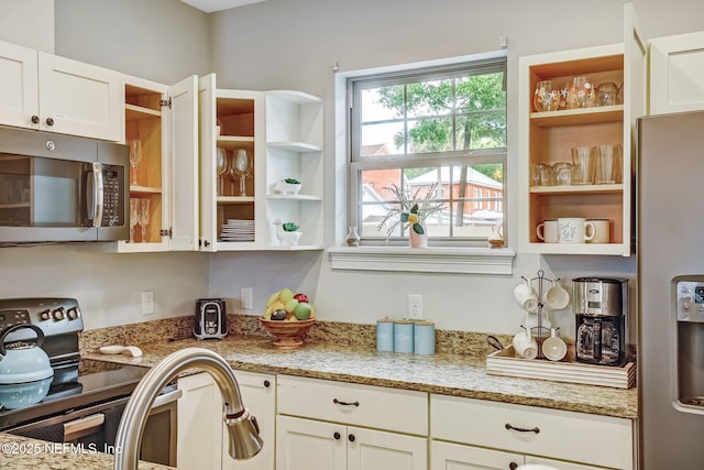 kitchen with white cabinetry, stainless steel appliances, and light stone countertops