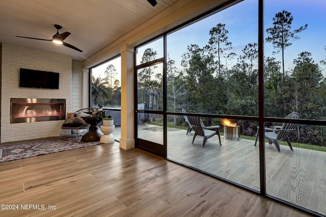 sunroom featuring a fireplace and ceiling fan