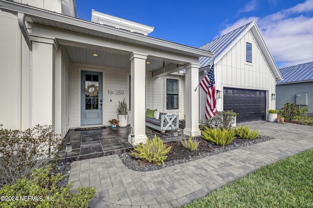 view of exterior entry with a garage and covered porch