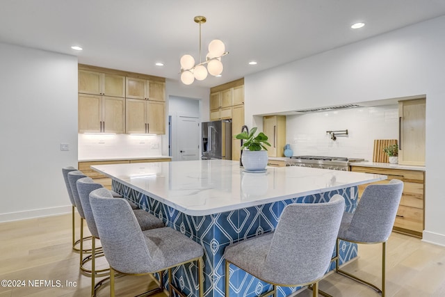 kitchen with a large island, pendant lighting, a breakfast bar, high quality fridge, and light wood-type flooring