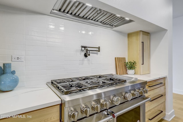 kitchen with premium range hood, double oven range, light stone counters, and light brown cabinets