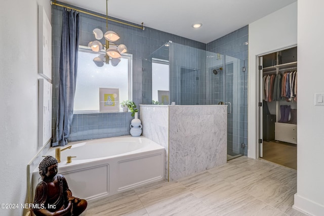 bathroom featuring a chandelier and separate shower and tub