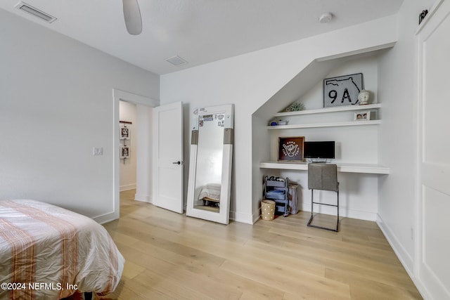 bedroom with ceiling fan, built in desk, and light hardwood / wood-style flooring