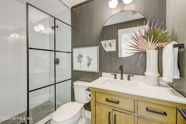 bathroom featuring vanity, a tile shower, and toilet