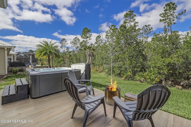 wooden terrace featuring a hot tub, a fire pit, and a lawn