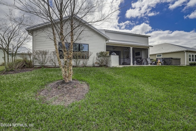 back of property featuring a yard, a jacuzzi, and a sunroom