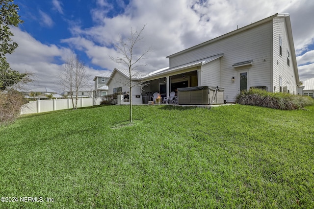 rear view of house featuring a yard and a hot tub