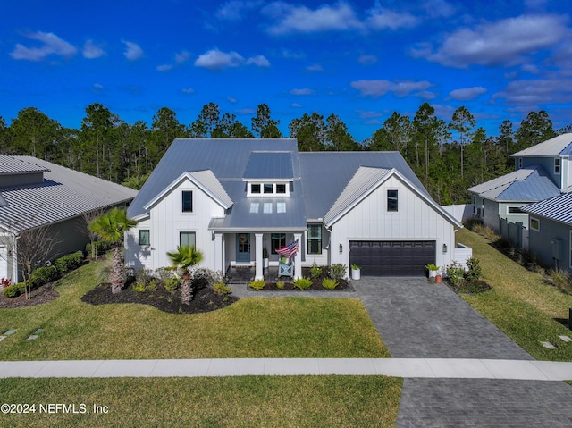 modern farmhouse featuring a porch, a garage, and a front yard