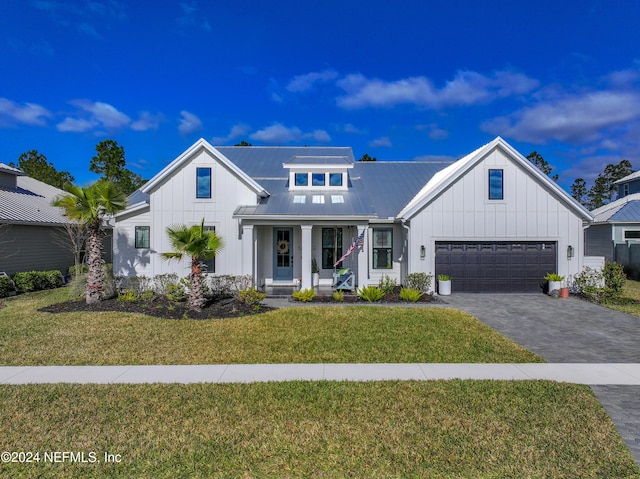 modern inspired farmhouse with a garage, a front lawn, and a porch