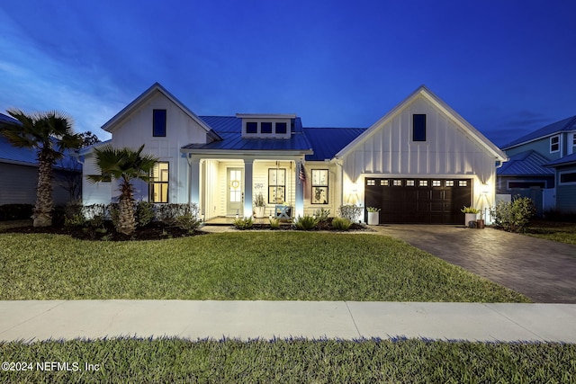 modern farmhouse style home featuring a porch, a garage, and a yard