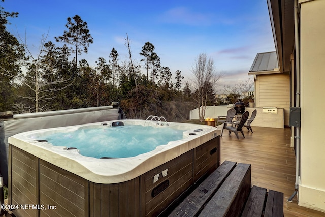 pool at dusk featuring a hot tub and a deck