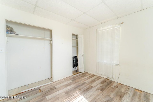 unfurnished bedroom featuring a paneled ceiling and light hardwood / wood-style flooring