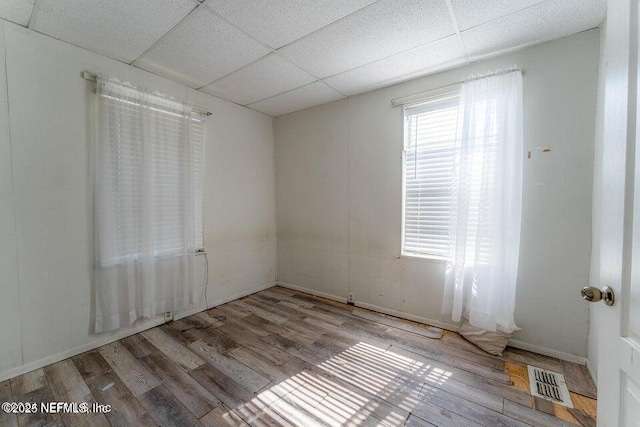 empty room featuring a paneled ceiling and light hardwood / wood-style flooring