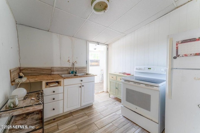 kitchen featuring sink, a paneled ceiling, light hardwood / wood-style flooring, white appliances, and white cabinets