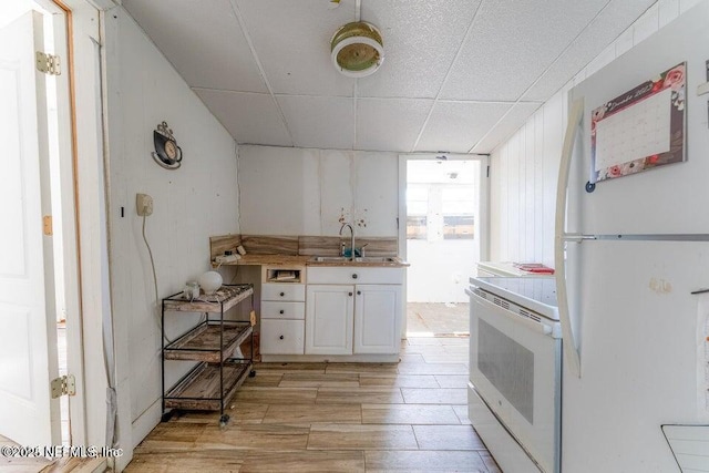 kitchen featuring sink, white cabinets, white appliances, and light hardwood / wood-style flooring