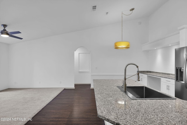 kitchen with stone countertops, white cabinetry, sink, stainless steel fridge, and hanging light fixtures