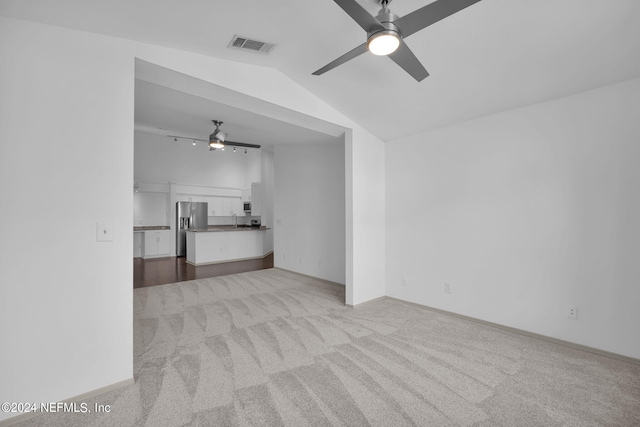 unfurnished living room with vaulted ceiling, light carpet, and ceiling fan