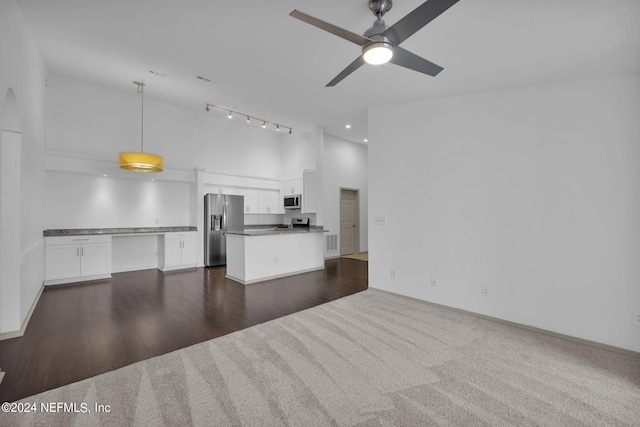 unfurnished living room with dark wood-type flooring, ceiling fan, and high vaulted ceiling