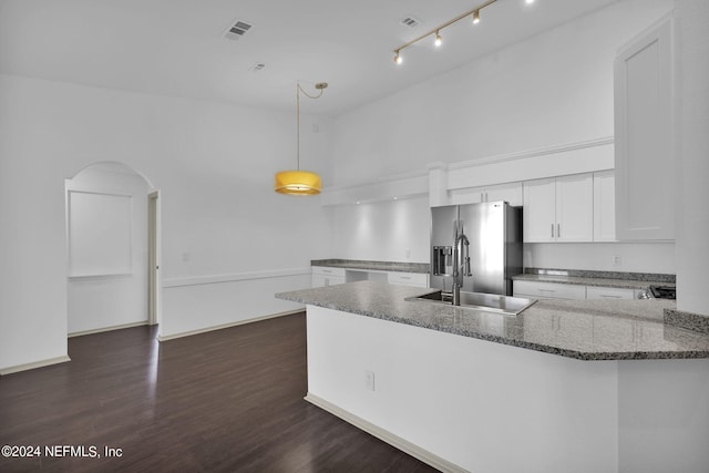 kitchen featuring dark hardwood / wood-style floors, white cabinetry, stainless steel fridge, dark stone counters, and hanging light fixtures