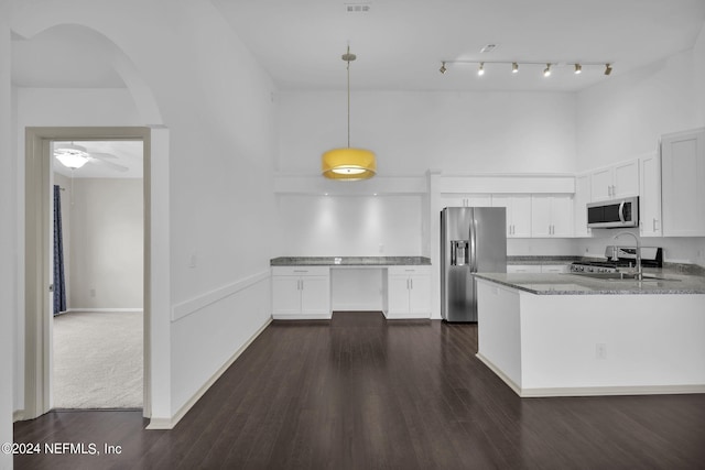 kitchen featuring stone counters, white cabinetry, hanging light fixtures, a towering ceiling, and stainless steel appliances