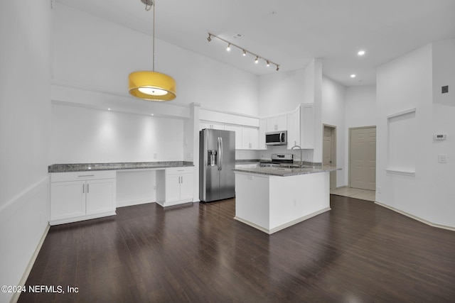 kitchen with appliances with stainless steel finishes, dark stone countertops, white cabinets, and decorative light fixtures