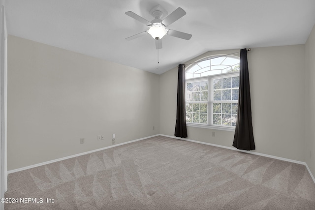 spare room featuring vaulted ceiling, light colored carpet, and ceiling fan