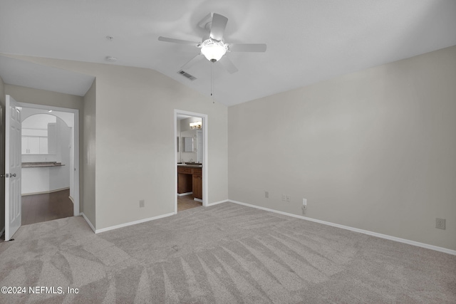 unfurnished bedroom with vaulted ceiling, connected bathroom, light carpet, and ceiling fan