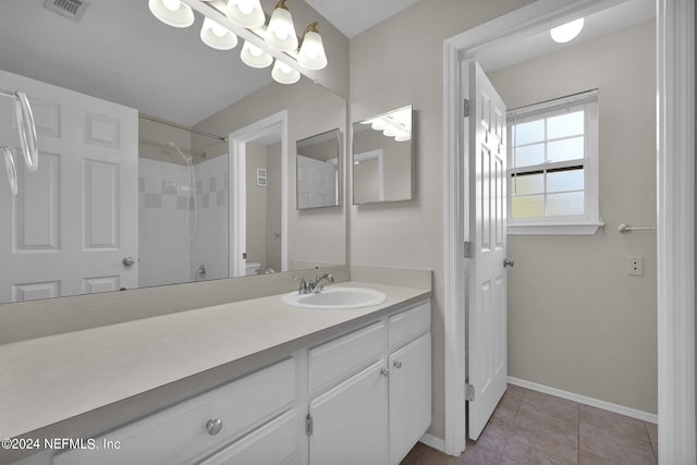 bathroom with tile patterned flooring, vanity, toilet, and a shower