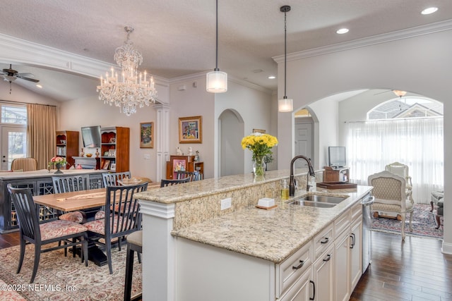 kitchen with sink, white cabinetry, decorative light fixtures, dark hardwood / wood-style floors, and a kitchen island with sink