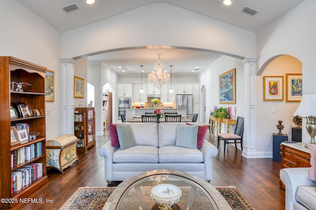 living room featuring ornamental molding, dark hardwood / wood-style flooring, decorative columns, and a notable chandelier