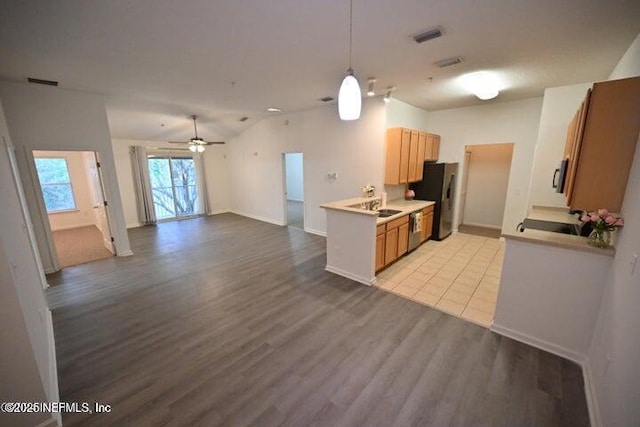 kitchen with lofted ceiling, light hardwood / wood-style flooring, stainless steel appliances, and ceiling fan