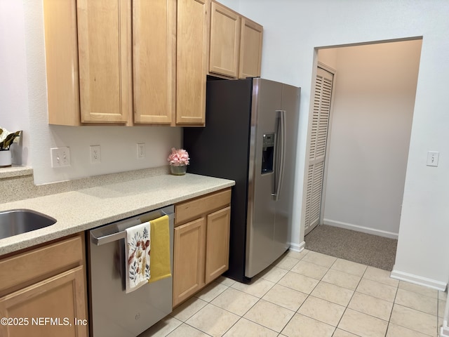 kitchen with stainless steel appliances, light tile patterned flooring, and light brown cabinetry