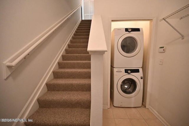 laundry area with light tile patterned flooring and stacked washer and dryer