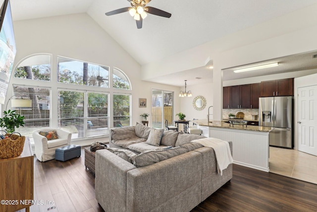 living room featuring ceiling fan with notable chandelier, dark hardwood / wood-style floors, and high vaulted ceiling