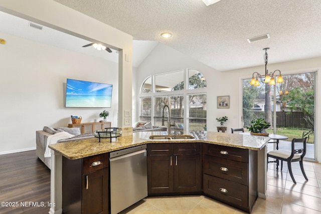 kitchen featuring dark brown cabinetry, sink, light stone counters, hanging light fixtures, and stainless steel dishwasher