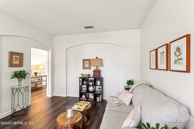 living room featuring dark wood-type flooring and a textured ceiling