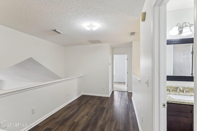 hall with dark hardwood / wood-style flooring, sink, and a textured ceiling