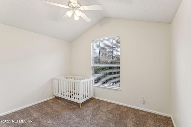 unfurnished bedroom with a nursery area, lofted ceiling, carpet flooring, and ceiling fan