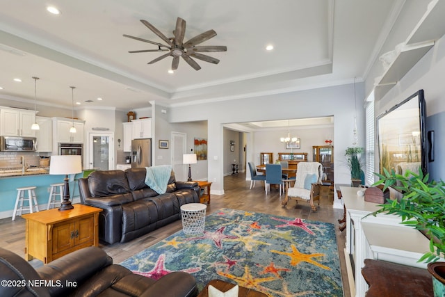 living room featuring light wood finished floors, crown molding, and a tray ceiling