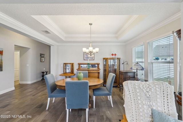 dining room featuring a tray ceiling, a notable chandelier, and wood finished floors