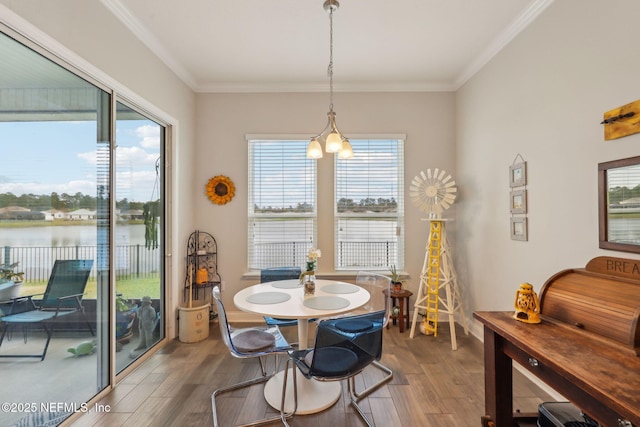 dining space with wood finished floors, a water view, and ornamental molding