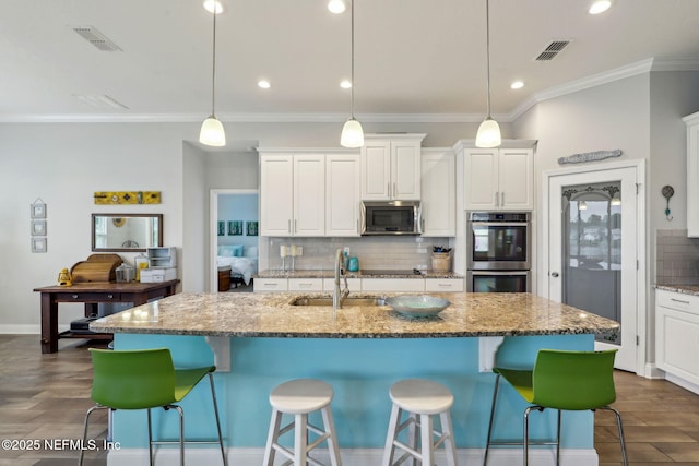 kitchen featuring visible vents, dark wood-style flooring, stainless steel appliances, and a sink