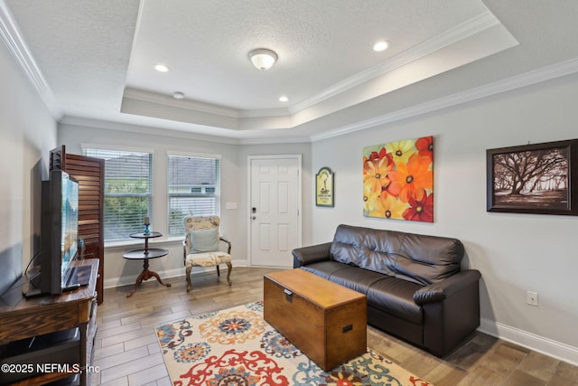 living area with a tray ceiling, crown molding, wood finished floors, and a textured ceiling